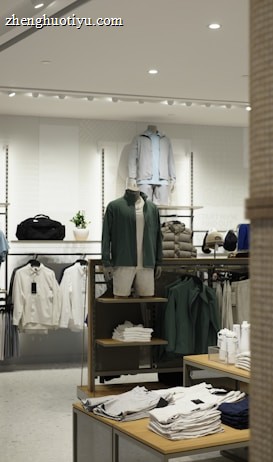 A retail clothing store display featuring mannequins dressed in casual, sporty attire including jackets and shorts. Shelves and racks are organized with neatly folded shirts and jackets in neutral and earthy tones. The lighting is bright and modern, enhancing the sleek display of garments and accessories.